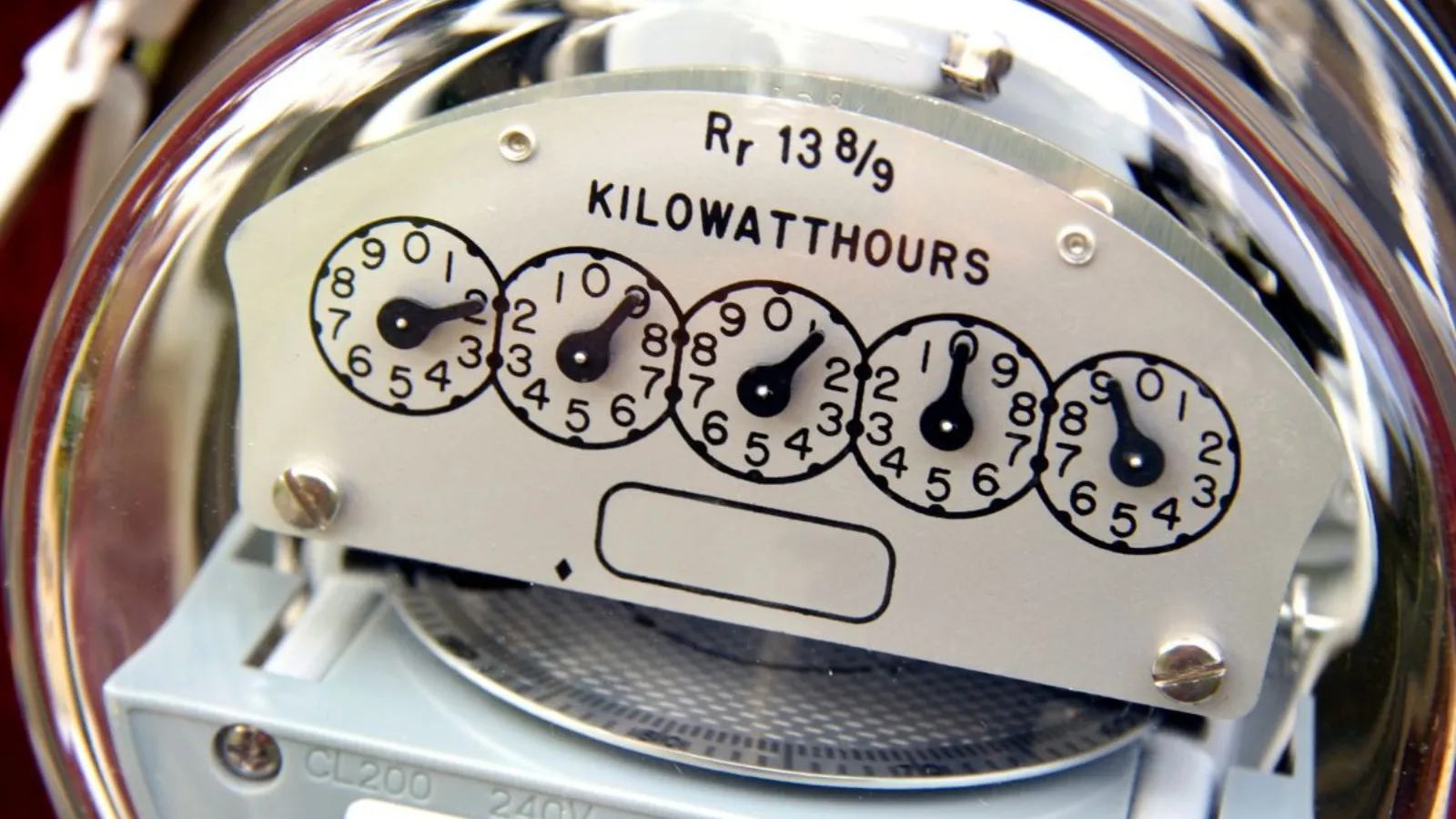 Close-up of an analogue electricity meter, its five dials behind a glass cover.